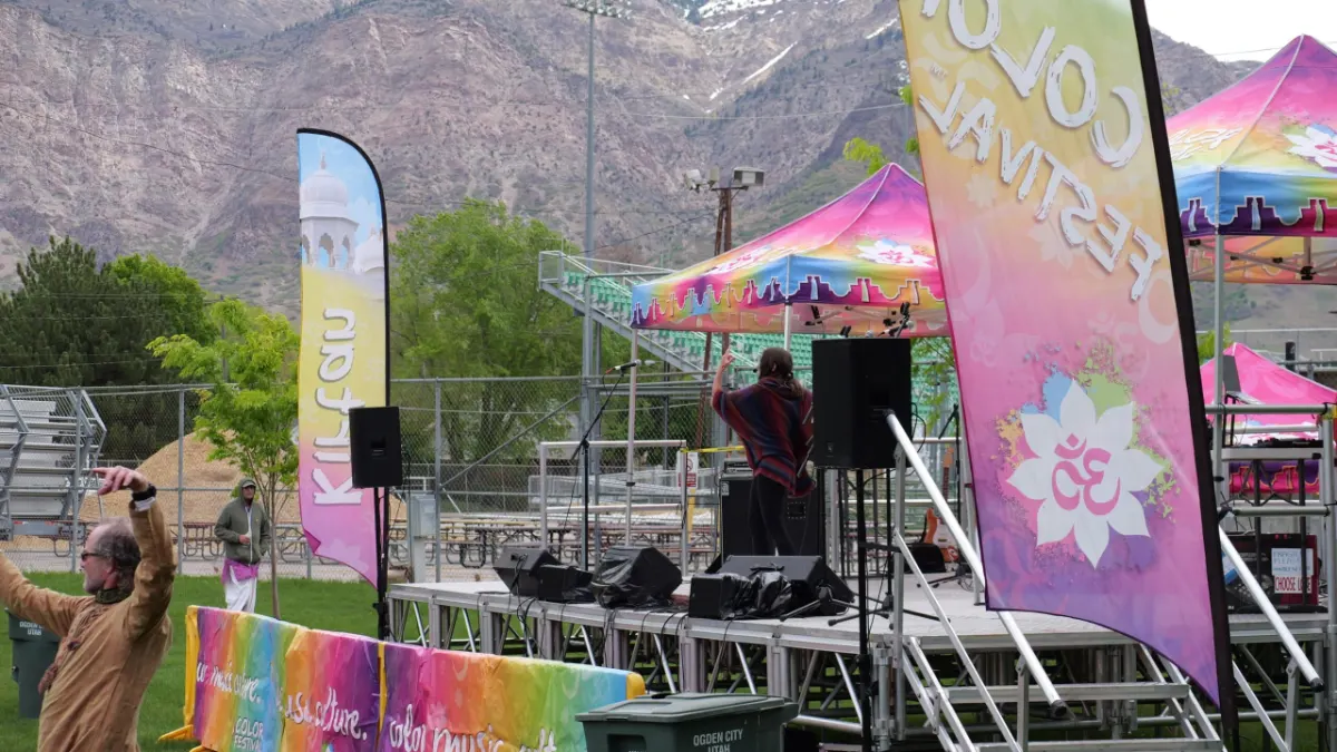 Festival stage with sound system, banners and canopy set up outdoors for the Festival of Colors in Ogden, Utah