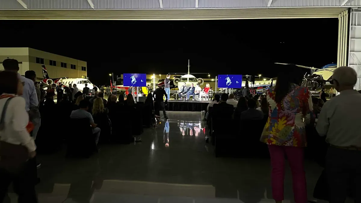 Guests watching the stage with a jet framed in the open hangar door