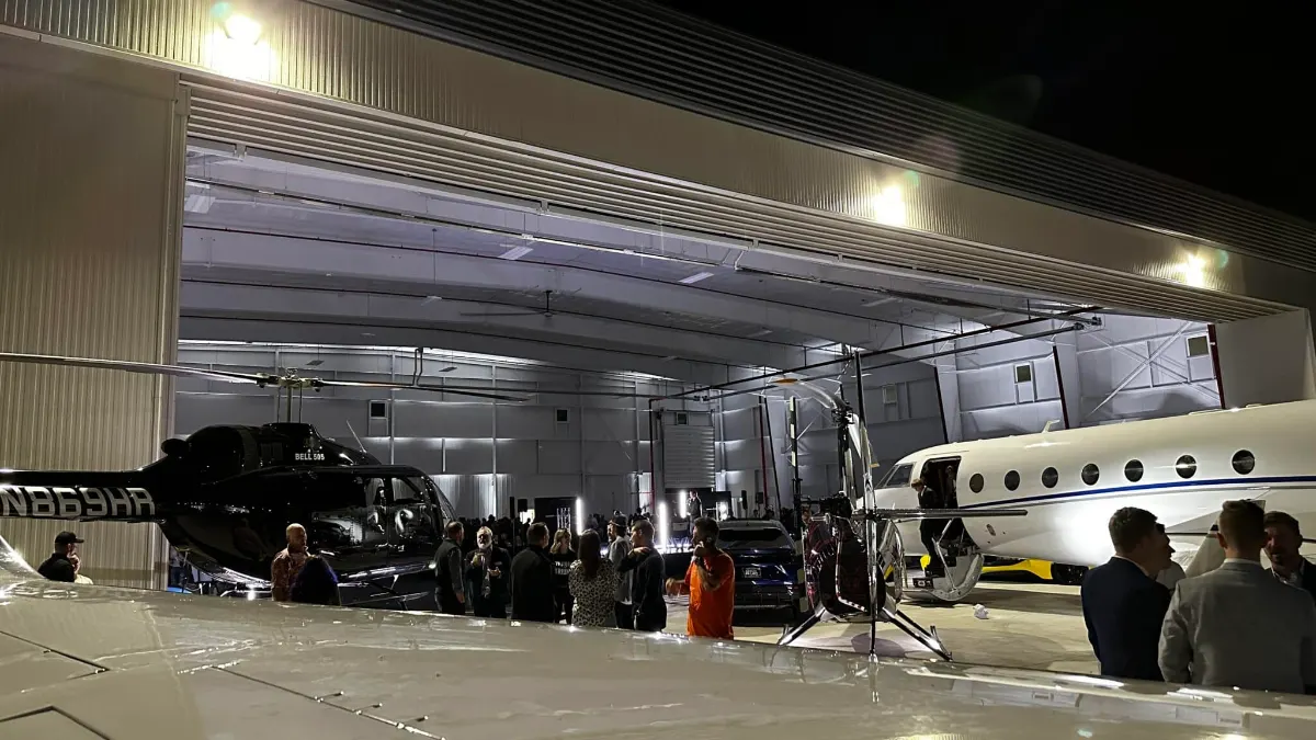 Provo Airport hangar during daytime load-in with a private jet and helicopter parked inside