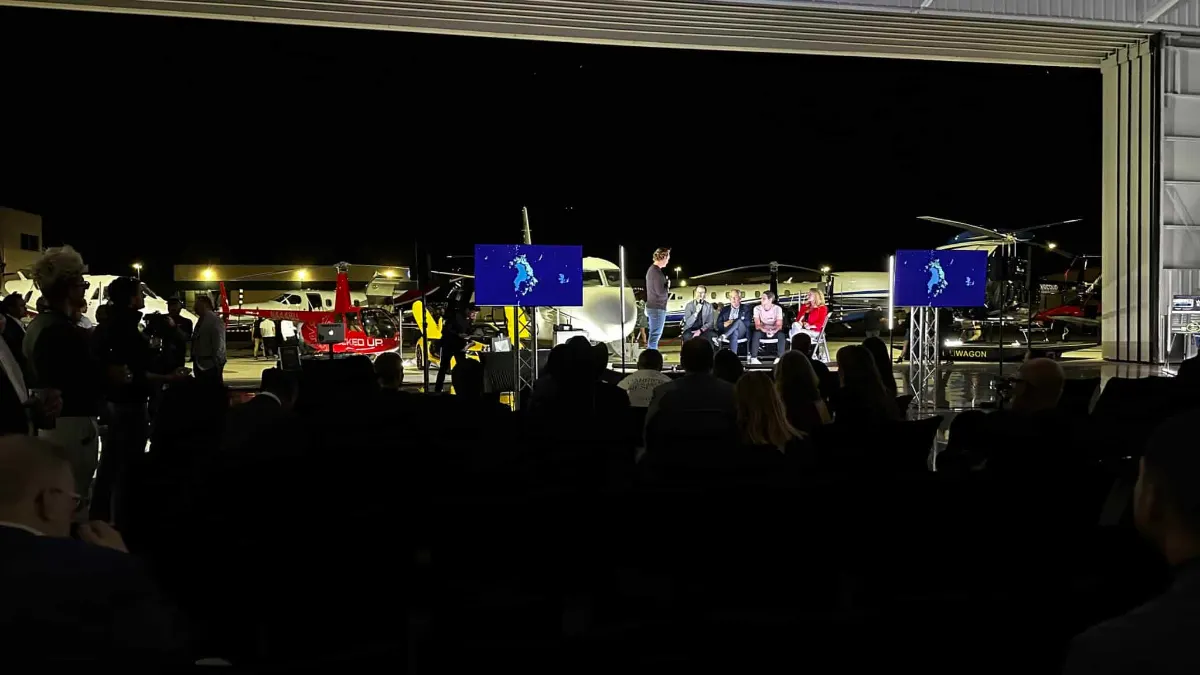 Wide view of the hangar with lit vehicles and blue stage screens