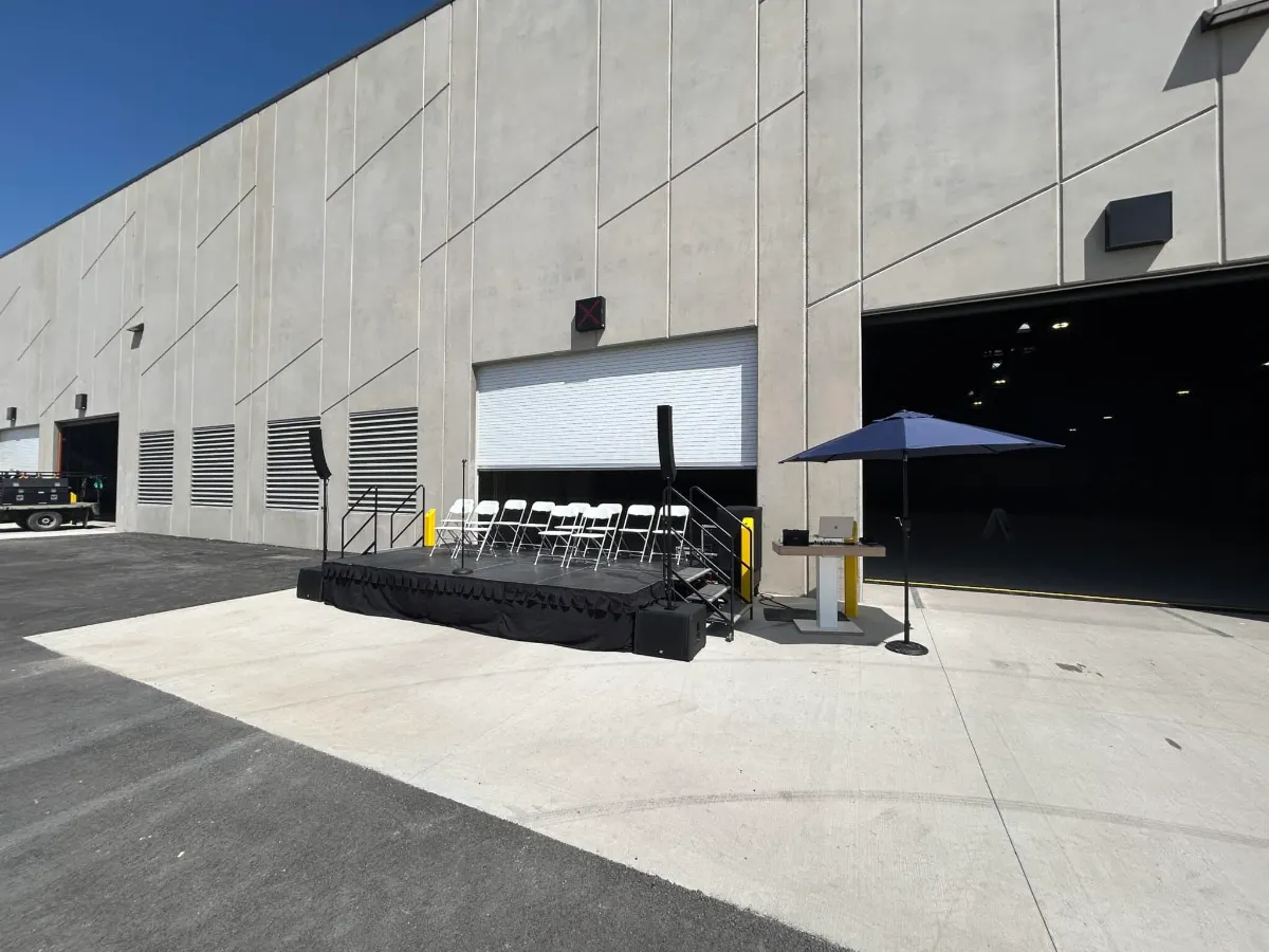 Stage with a shade canopy set against the building's open bay doors