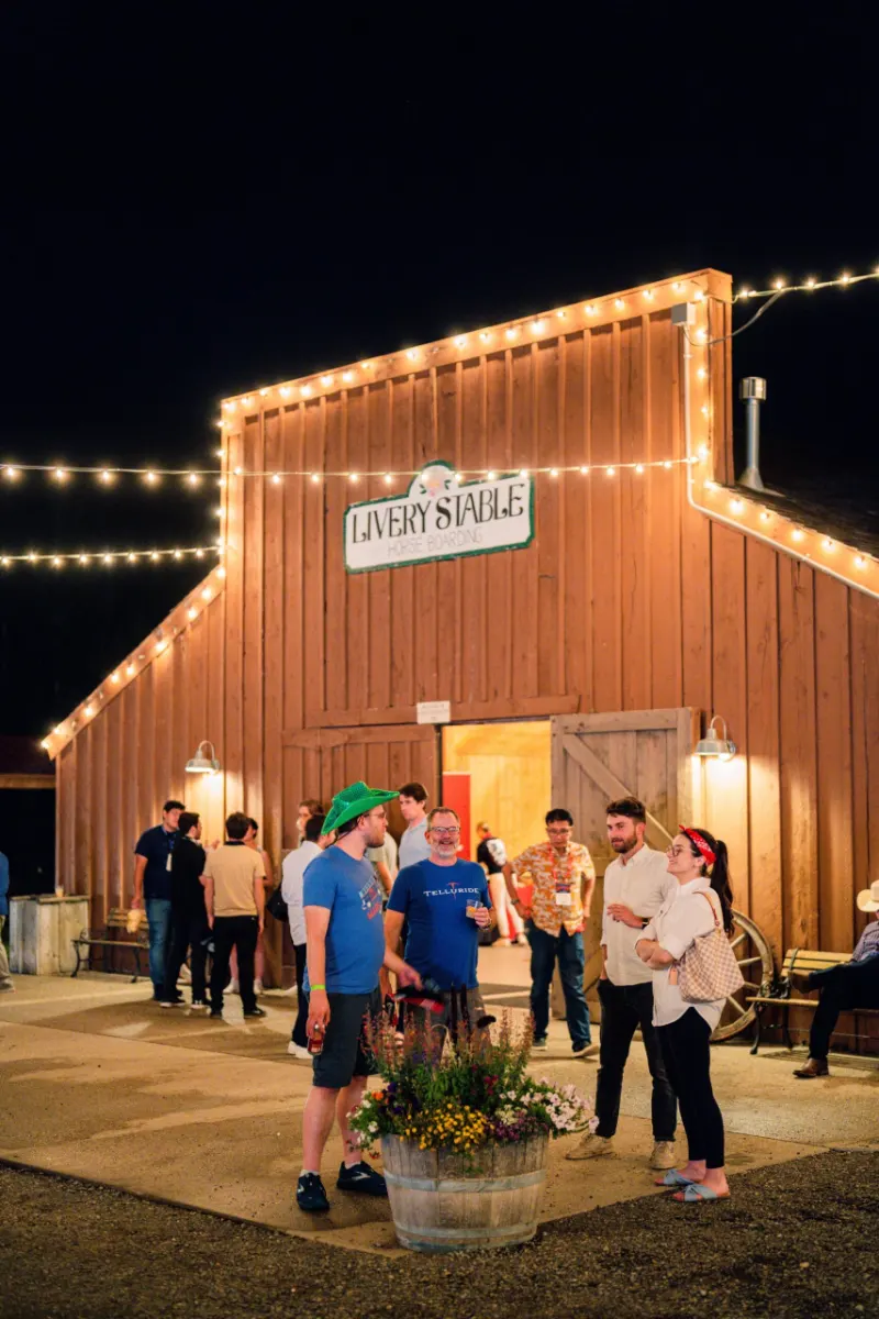 Guests outside a barn venue under string lights in the evening