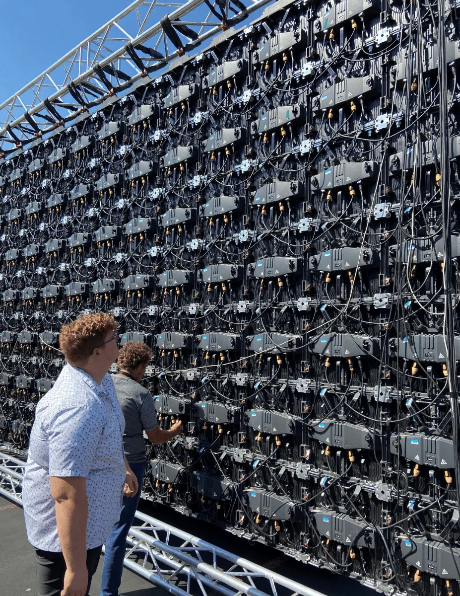 Crew building a large mobile video wall panel by panel on a truss structure