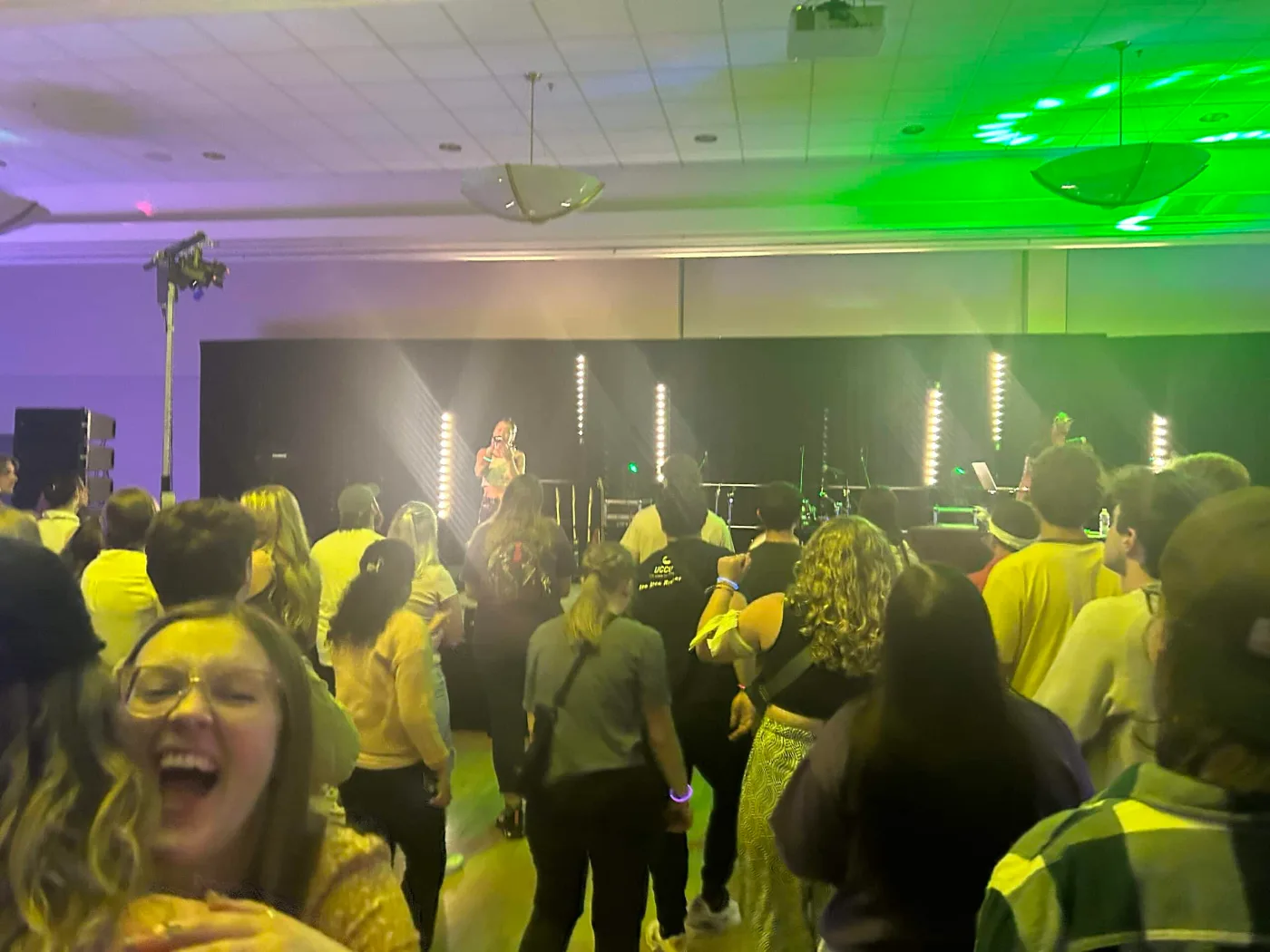 Students packed in front of the WeberChella stage under green and purple concert lighting