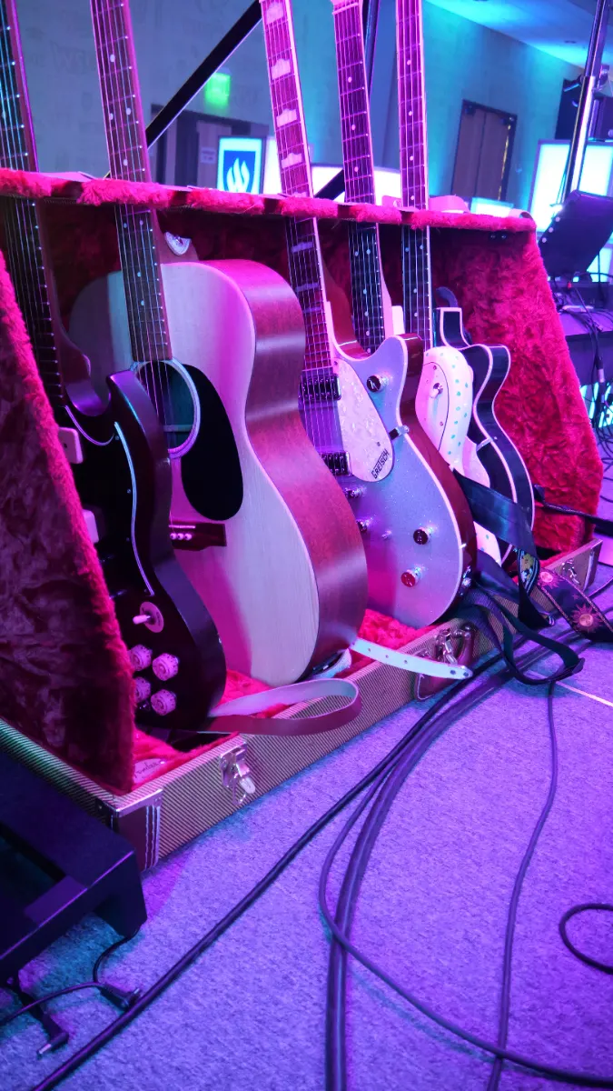 Row of guitars on stands as backline beside the stage
