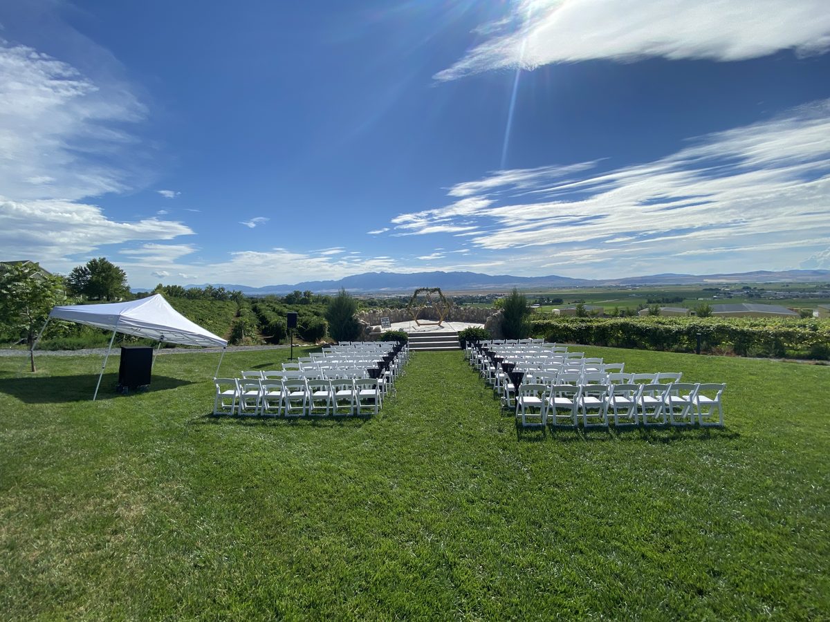 Sweeping event lawn with rows of white chairs, a tent, and big mountain views